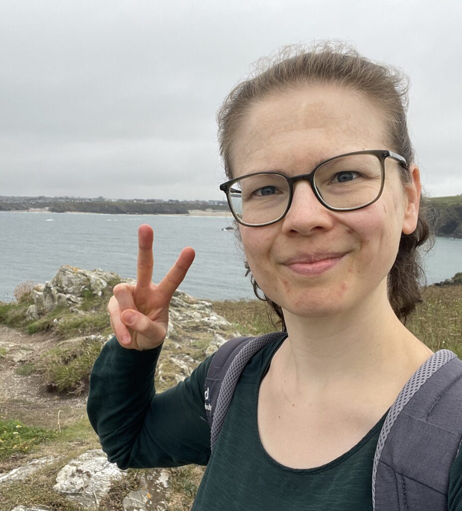 Juliane (Jule) Becher, lächelt auf einem Urlaubsfoto am Meer, in die Kamera.
