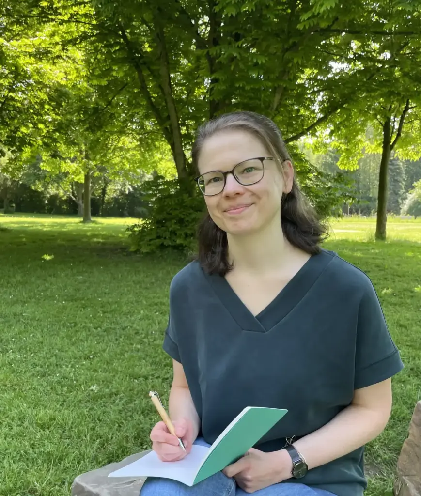 Foto_Juliane Becher_outdoor arbeiten Juliane Becher sitzt in der Natur und schreibt Ideen in ein Notizbuch