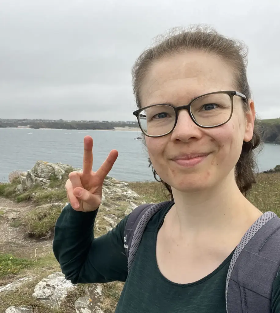 Jule_Die_Content-Macherin_Foto_Über mich Juliane (Jule) Becher, lächelt auf einem Urlaubsfoto am Meer, in die Kamera.