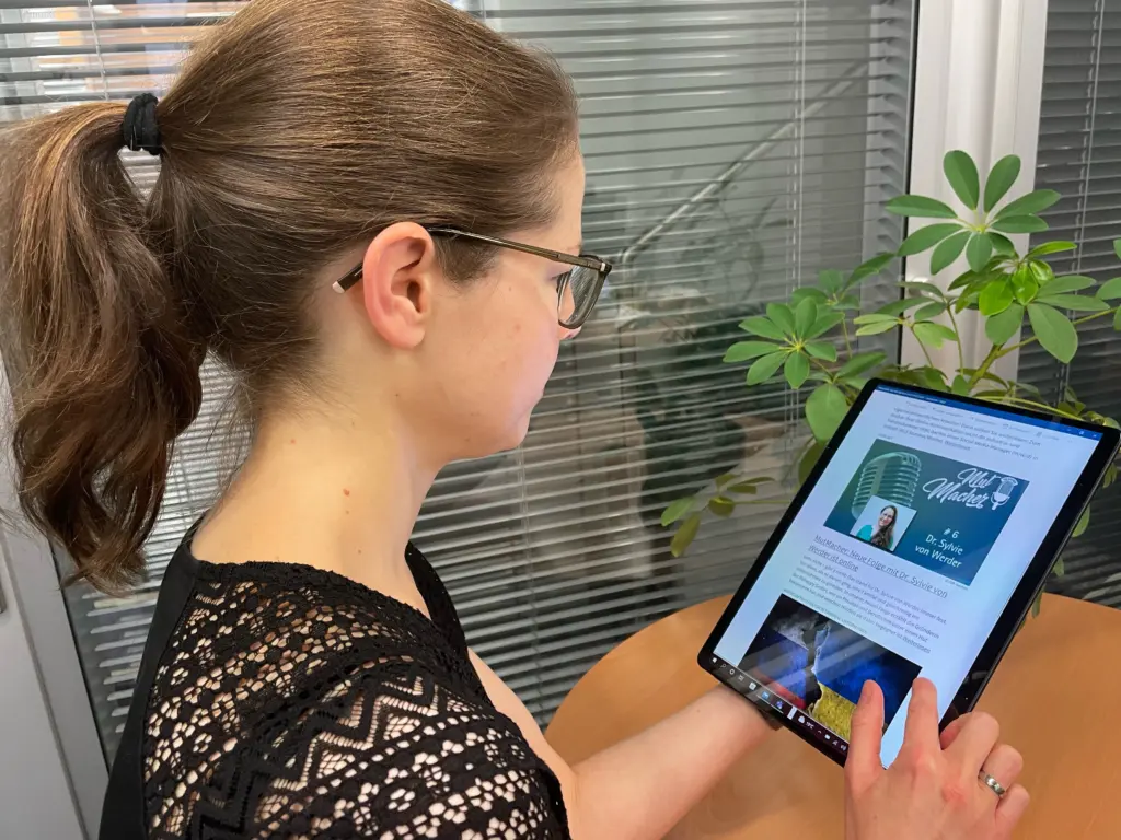 Juliane Becher tablet Juliane Becher bedient ein Tablet, auf dem News angezeigt werden.